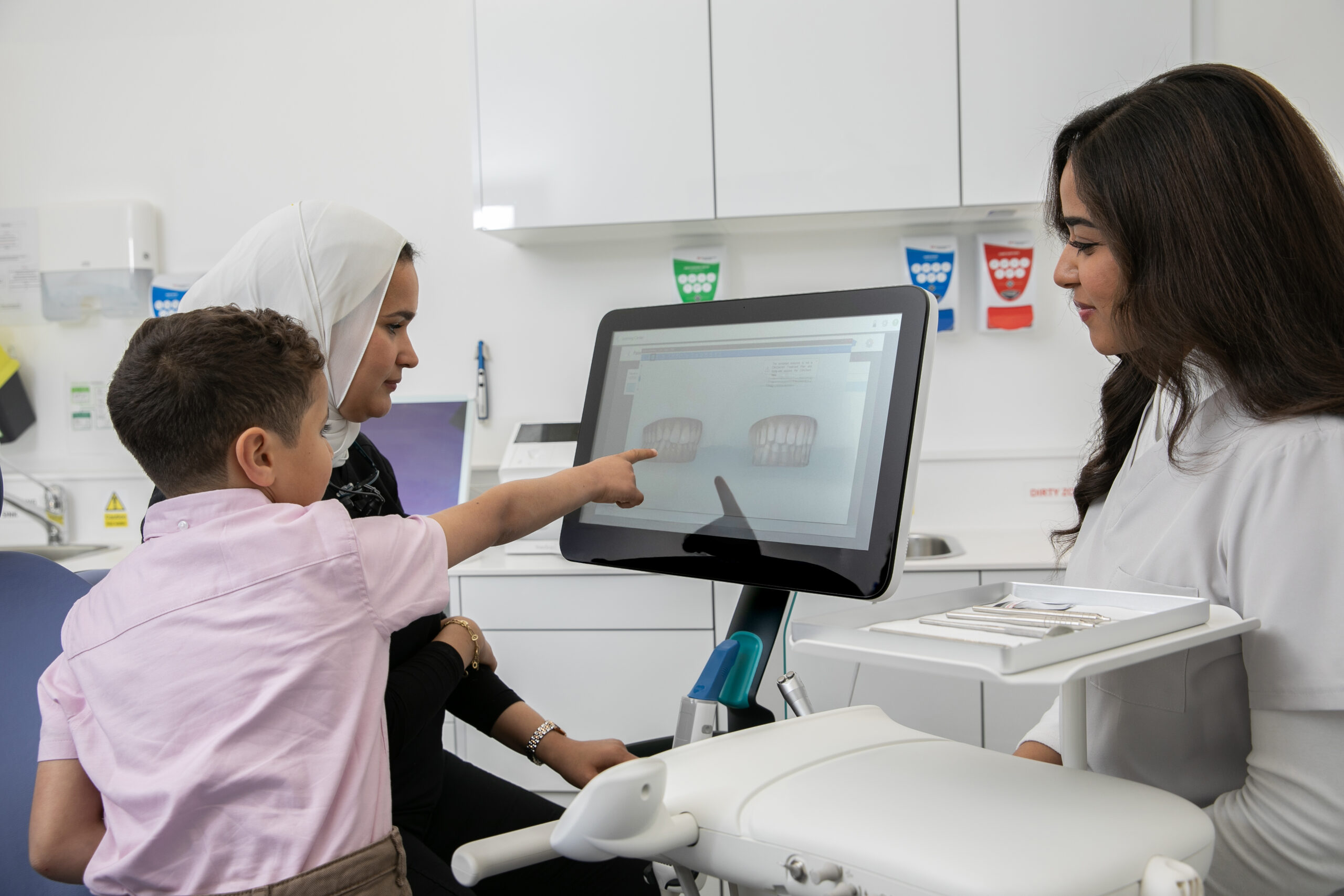 A child and an adult looking at a dental scan on a screen with a member of the practice team.