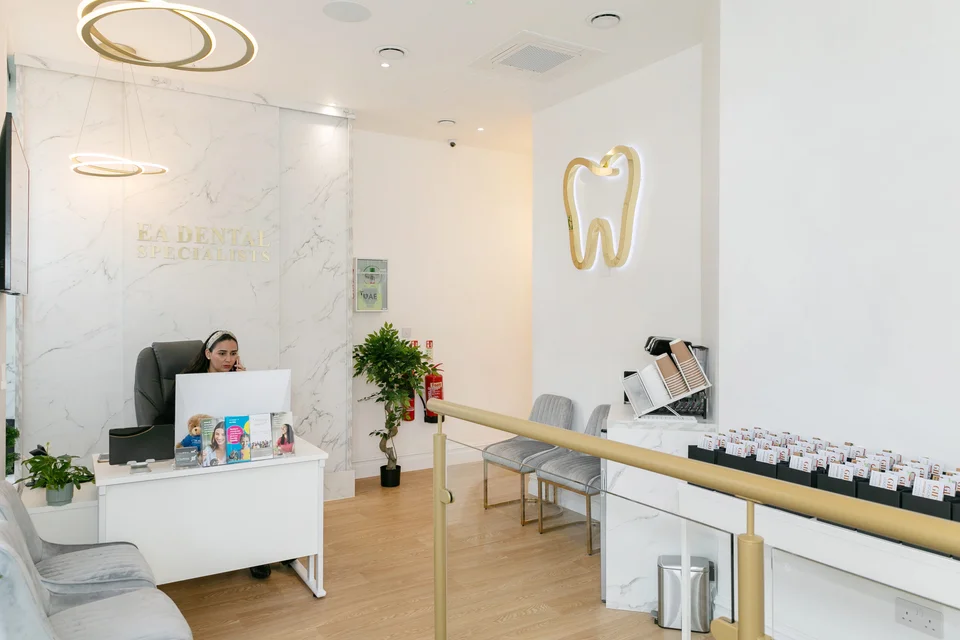 EA Dental Specialists reception with a marble desk, gold lighting and grey seating.