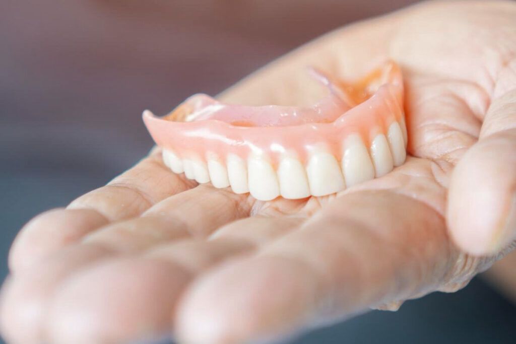 Hands holding a complete removable denture.